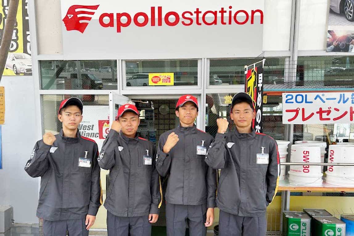 アポロステーションの店舗前で、笑顔でガッツポーズをして並ぶ4人のスタッフ